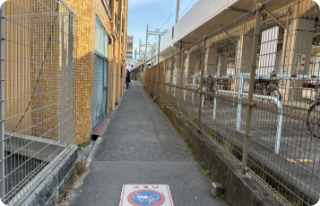 右に曲がりまっすぐ行くとローソンが見えてきます。そのまま高架沿いにまっすぐ進んでください。右手は駐輪場になっています。